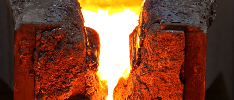 Incandescent refractory material with a central crack glowing bright orange from intense heat or molten material.