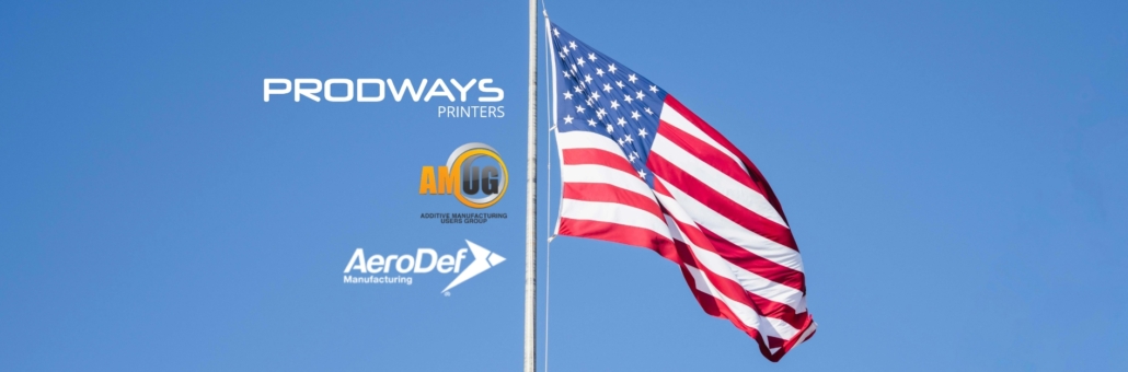 Prodways Printers logo alongside AMUG and AeroDef Manufacturing logos next to a waving American flag against a clear blue sky